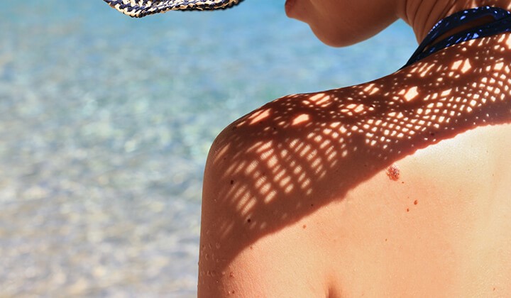 Frau blickt über Schulter Wasser-in-Öl-Emulsion als Sonnenschutz für trockene Haut
