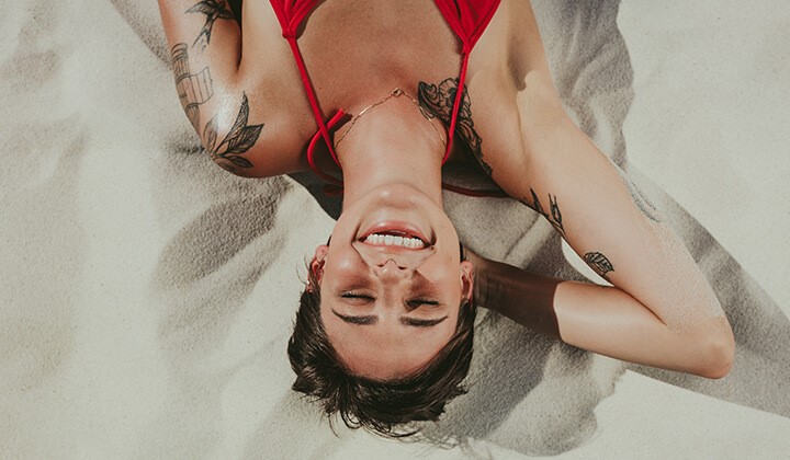 Frau mit Tattoos genießt die Sonne In der Sonne das Tattoo schützen