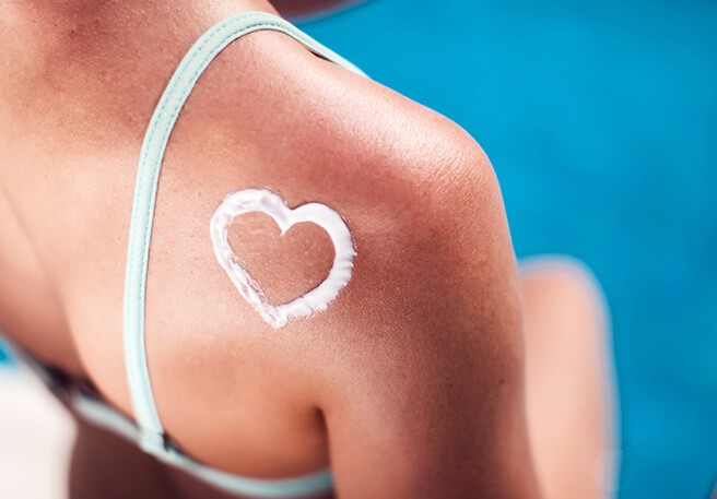 Frau mit Herz aus Sonnencreme auf der Schulter Sonnencreme & Verträglichkeit sind vielen wichtig