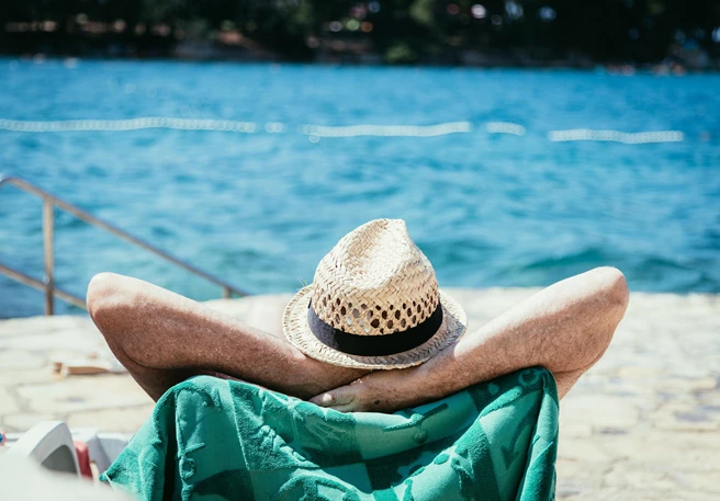 Mann sonnt sich am Strand Sonne & Krankheiten wie Mallorca Akne