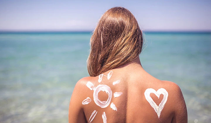 Frau mit Sonnencreme auf dem Rücken Sonnencreme richtig auftragen