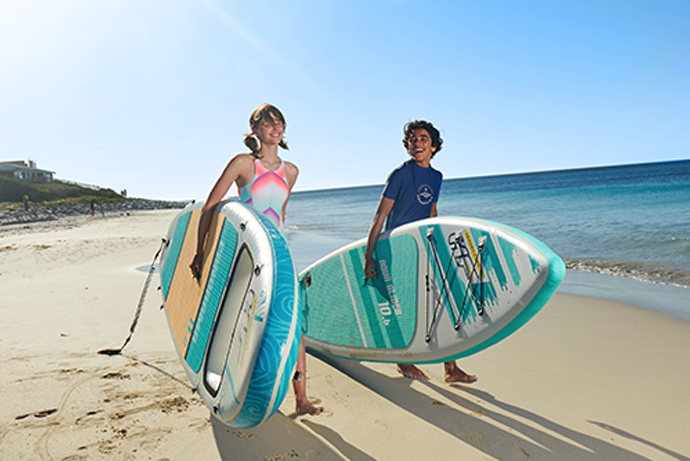Jugendliche mit SUPs am Strand