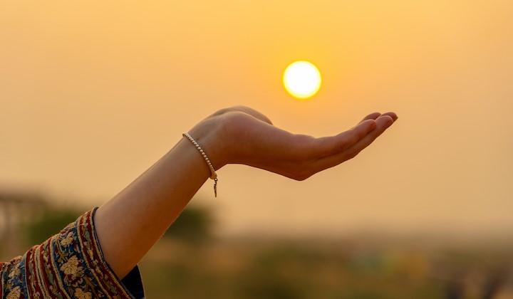 Hand mit Sonne im Hintergrund Ratgeber Sonne & Haut