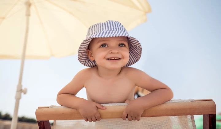 Kind mit Sonnenhut am Strand Unterschiede Kindersonnencreme & normale Sonnencreme